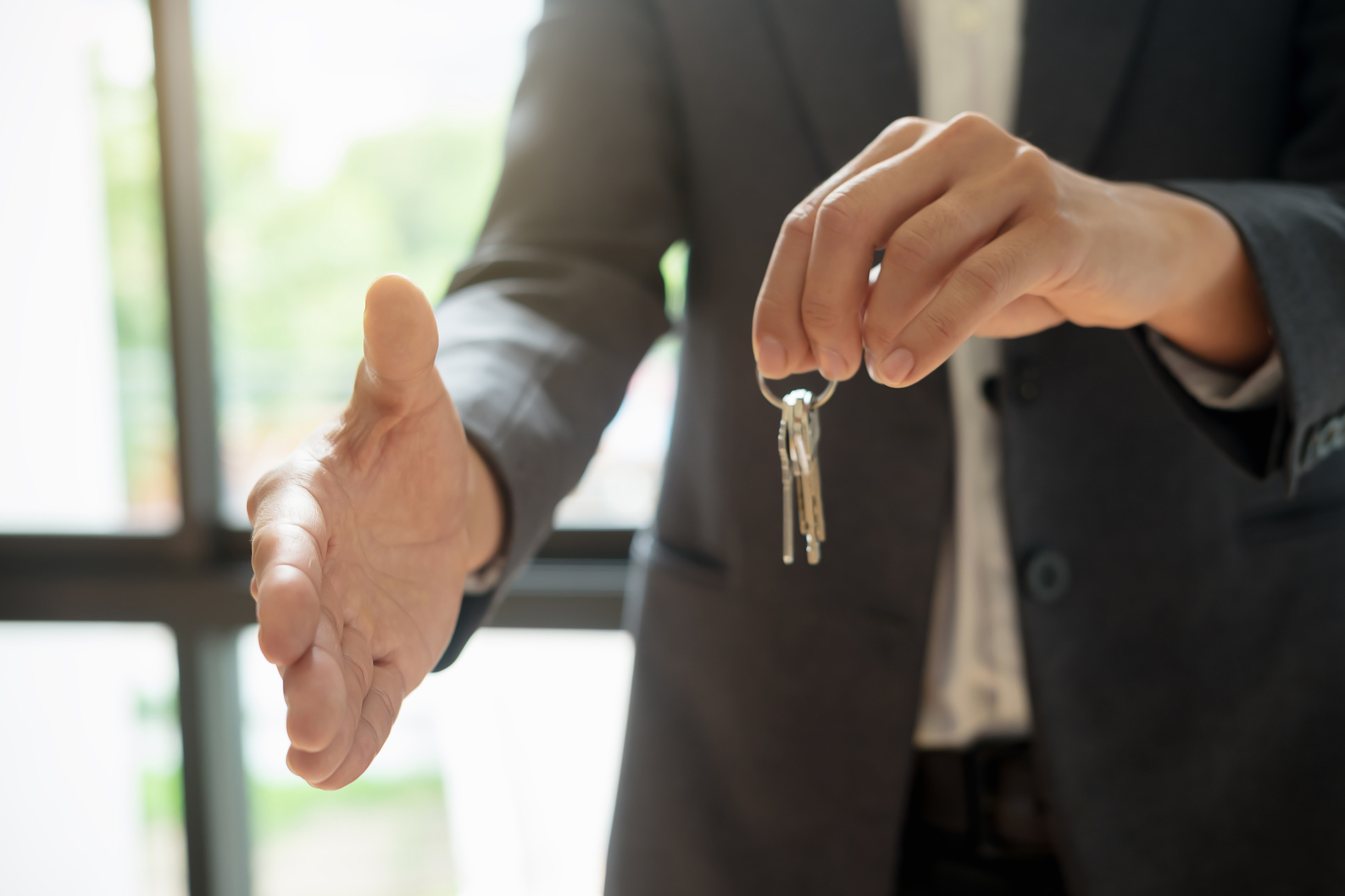 Real Estate Agent Holding Keys Gesture a Handshake